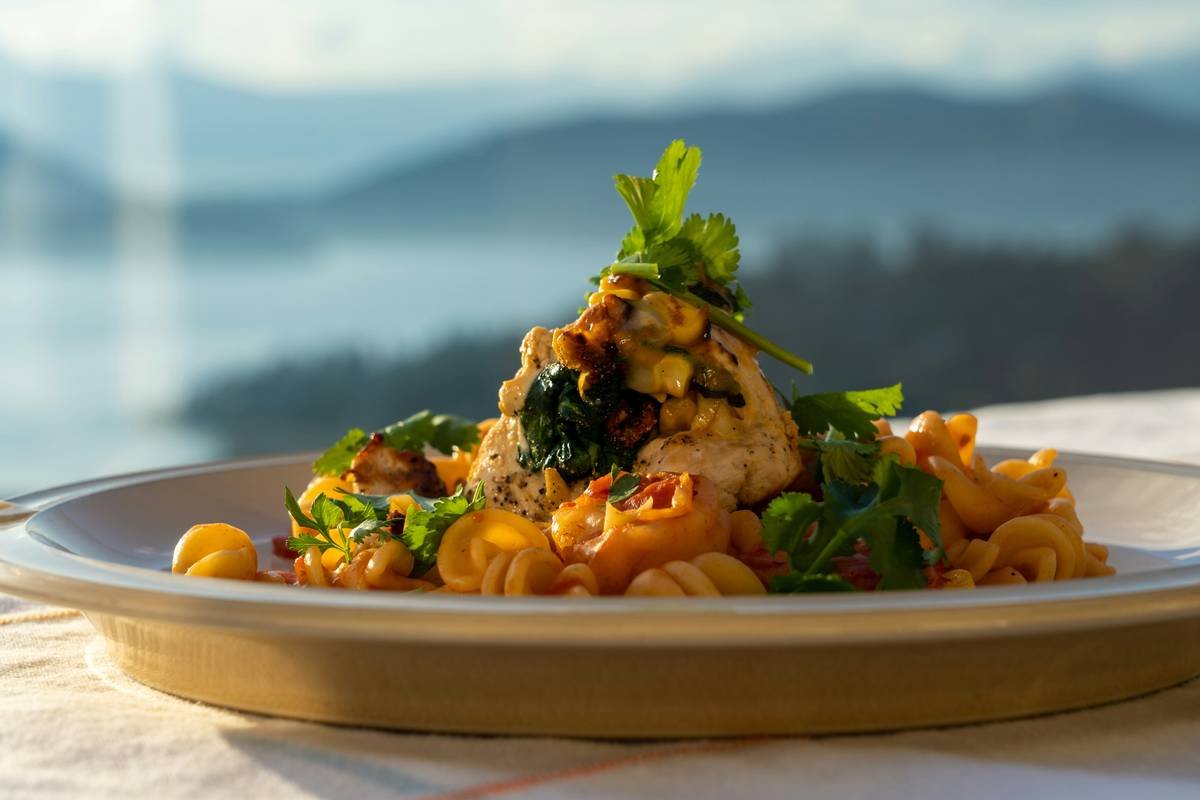 chicken and pasta in front of blurred mountains and ocean.